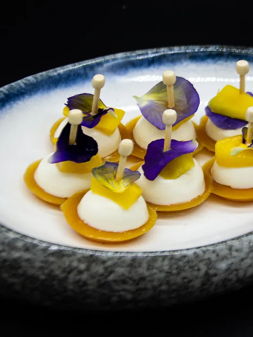 Bouchées garnies de fleurs de pensée sur une assiette de grès